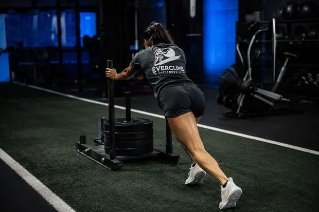 Athlete pushing a weighted sled in EverClimb training apparel